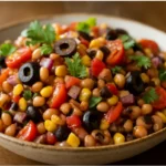 cowboy caviar dip recipe in white bowl with tortilla chips and garnish